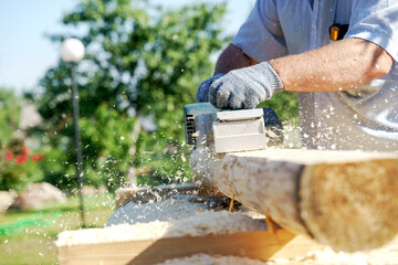 a carpenter works with an electric pipe on a sunny day