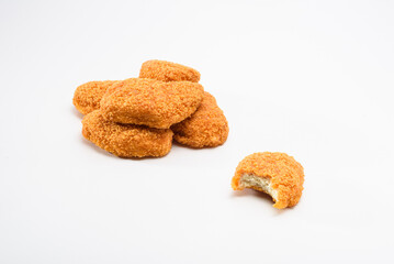 Pile of yummy chicken nuggets, with a bitten nugget on the front, isolated 