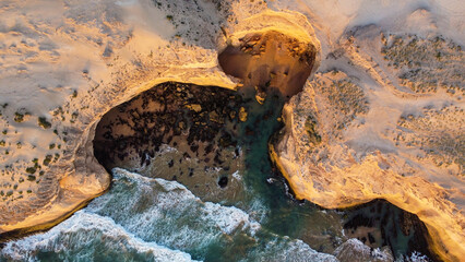 Elevated, birds eye view of ocean water surface with tough waves and cliff rocks. Nature texture...