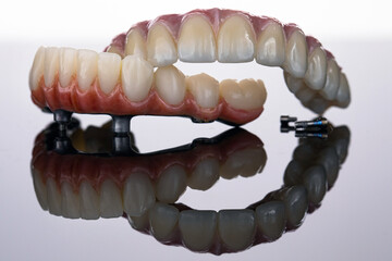 two dental prostheses of the upper and lower jaws with a beautiful gum on a white background with reflection