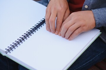 Blinded man reading by touching braille book