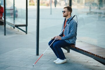 Blinded man waiting for bus at a bus station