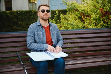 Fototapeta premium Blinded man reading by touching braille book