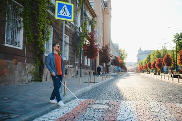 Blind person with white cane crossing street in city, closeup