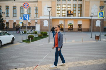 Handsome blind man walks around the city.