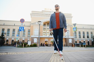 Handsome blind man walks around the city.
