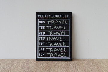 A board with a weekly schedule on which the word travel is written from Monday to Sunday. It is...