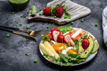 Ketogenic diet. Fried egg, avocado, strawberry, grilled chicken fillet, cheese, nuts and arugula, Low carb high fat breakfast, top view