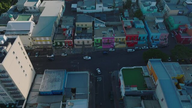 High angle view of vehicles passing road intersection in town. Brightly coloured houses in residential Bo Kaap neighbourhood. Cape Town, South Africa
