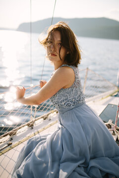 Calm young lady looking at camera while sitting on sailboat
