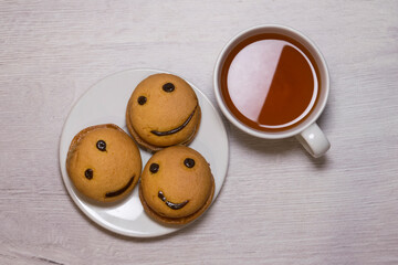 Top view smile cookies on a white plate with a cup of tea. Sweet biscuit. Tasty food.