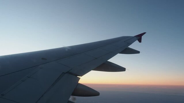 Wing of airliner in flight during sunset.