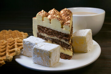 Piece of cake with turkish delight on white plate and waffles.