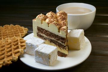 Piece of cake with turkish delight on white plate and waffles.