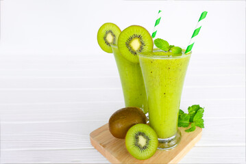 Kiwi yogurt fruit juice smoothie and green kiwi juice drink healthy, delicious taste in a glass for weight loss on a white wooden background.