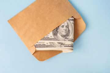 Stash of money in dollar bills coming out of an envelope on a blue background. The concept of salary, bribe, loan, debt, win. - obrazy, fototapety, plakaty