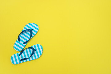 beach baby flip flops on yellow background with copy space