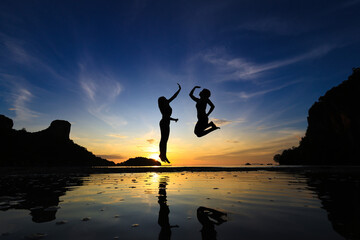Silhouette Joyful women jump over Railay beach at Krabi of Thailand , morning exercise healthy lifestyle