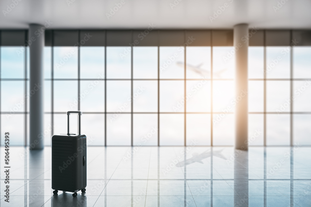 Poster Business travel concept with hand suitcase in empty waiting area airport hall with glossy floor, columns and plane taking off behind huge window. 3D rendering