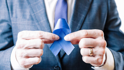 Cancer people prostate. Business man with blue ribbon in hands on white background. Awareness...