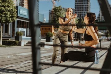 Young women in sportswear exercising on a river promenade
