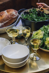 three glasses of white wine on table with salad, mussels, bread. evening meal dinner