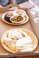 Cheese, olives, and bread served on eco-friendly plant-based plates and cardboard tray for a friendly party in a winery, bar or restaurant.