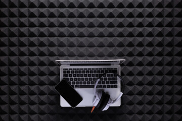 Music headphones and laptop on acoustic foam background texture. Music equipment concept studio