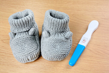 Gray bootees with a pregnancy test on a table