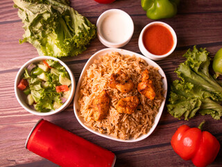 chicken tikka biryani in a dish served with salad, raita, sauce and drink top view of indian and pakistani biryani deal