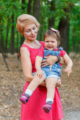 Fototapeta premium beautiful mother with her daughter walks in the park in summer