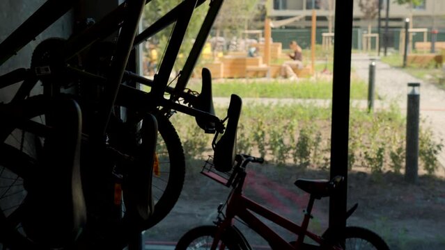 Parking for bicycles inside the building with panoramic windows. Stock footage. Parked bicycles for children and adults indoors.