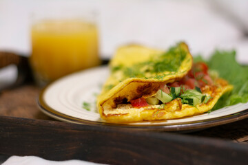 Close-up of a breakfast tray with scrambled eggs with herbs and a glass of orange juice in a stylish white bed no people. Concept: healthy breakfast in bed on a tray 