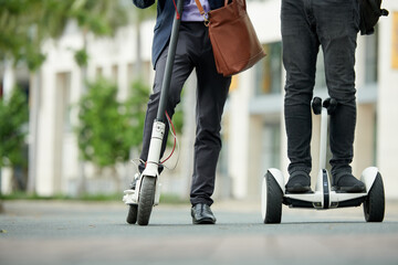 Cropped image of university lecturers riding on electric scooters to campus