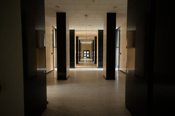 Fancy hallway of an office building, with walls in marble and pilars in shine black granite