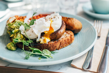 Healthy breakfast from poached eggs, grilled halloumi, Scrambled smoked harissa tofu, smashed avocado, grilled mushrooms and tomato beans on toast