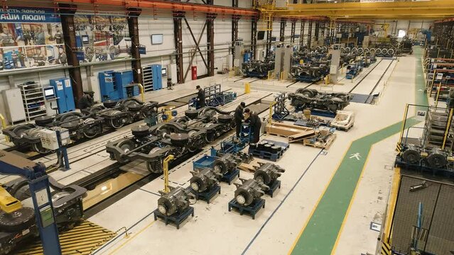 The drone flies in the assembly shop of the railway depot. Assembling the chassis for subway cars. Workers in masks perform work on the assembly line of the wheel frame of the train