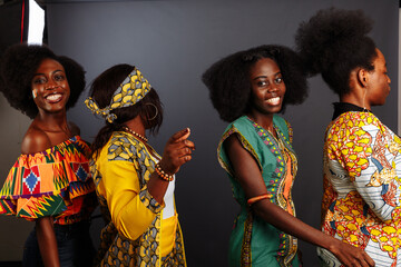 Four young beautiful African fashion models have fun and laughing in traditional dress. Women from the Congo Republic, Ivory Coast, and Zimbabwe - obrazy, fototapety, plakaty