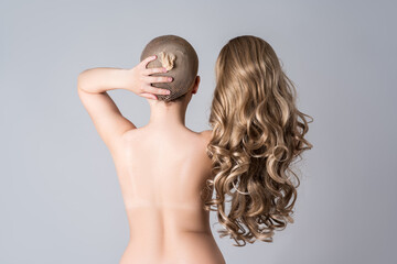 Topless woman with curly blonde wig on gray background, naked female back