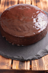 Carrot cake, covered in chocolate on stone surface over rustic wood, selective focus.