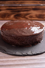 Carrot cake, covered in chocolate on stone surface over rustic wood, selective focus.