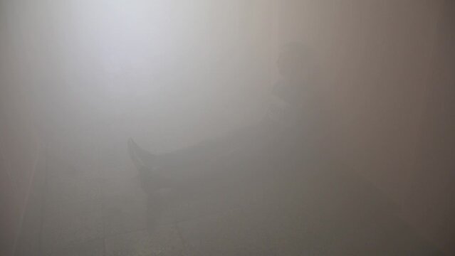 Catastrophe. A man sits on the floor unconscious in a hallway in thick smoke