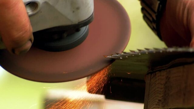 Old rusty hand saws are sharpened. Sparks fly from the saw