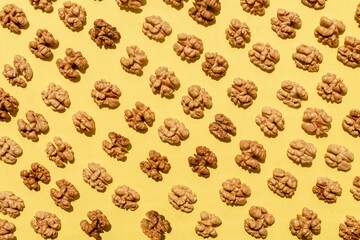 Seamless pattern of open walnuts on yellow background.