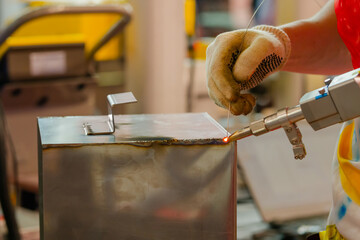 Welder hands using portable handheld laser welding machine - close up. Manufacturing, industrial,...