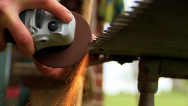 Old rusty hand saws are sharpened. Sparks fly from the saw
