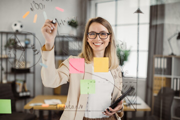 Young female developer smiling and looking at camera while working in creative office environment....