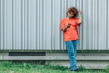 urban casual girl with mobile phone on wall outdoors