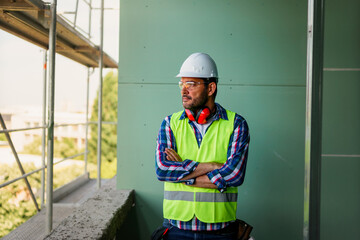 Portrait of men in 40s, construction worker. He is standing in construction and posing for camera.