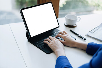 A business woman using blank white screen tablet computer with a calculator to calculate budget documents on his desk